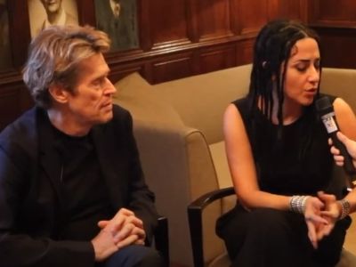 Giada Colagrande is speaking to the mic of the interviewer as Willem Dafoe is looking on.